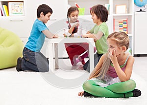 Little girl sitting apart - feeling excluded by the others