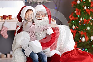 Little girl sitting on authentic Santa Claus` lap