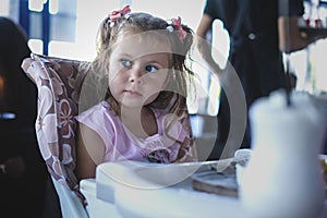 Little girl sitting on a baby chair in a restaurant