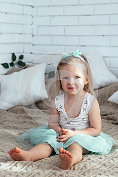 A little girl is sitting on the bed