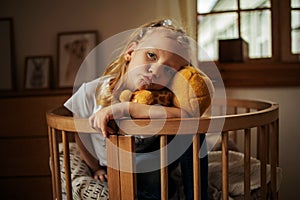 A Little Girl Sitting On The Bed In A Hug With Her Teddy Bear. Child, Home.