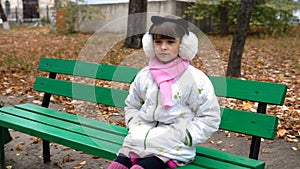 Little girl sitting on the bench in the park