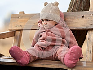 Little girl sitting on a bench in the park