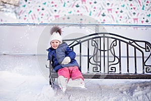 Little girl sitting on a bench in the skating rink