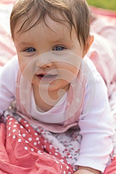 Little girl is sitting on blanket in garden