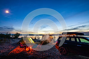 Little girl sitting at bonfire in tourist camping  in the evening