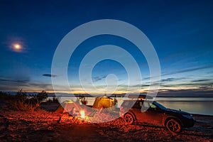 Little girl sitting at bonfire in tourist camping  in the evening