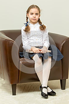 A little girl is sitting on a chair.
