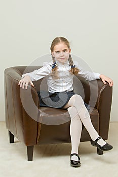 A little girl is sitting on a chair.