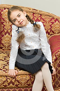 A little girl is sitting on a chair.