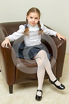 A little girl is sitting on a chair.