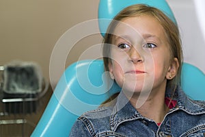 little girl sitting in a chair near a dentist after dental treatment. Little girl sitts in the dentist\'s office