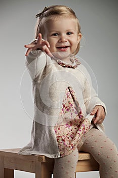 Little girl sitting on chair is pointing