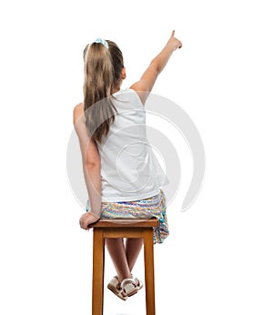Little girl sitting on chair and pointing aside