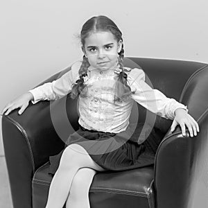 A little girl is sitting on a chair.A sweet blonde with long wattled