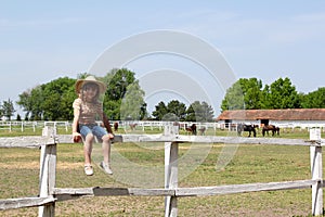 Little girl sitting on corral