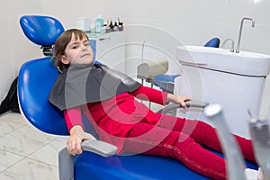 A little girl is sitting in a dental chair in the dentistÃ¢â¬â¢s dentistry photo