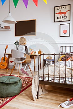 Little girl sitting at desk in her stylish vintage bedroom with workspace