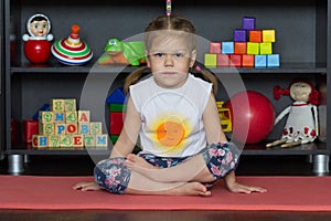 Little girl sitting in easy or lotus yoga pose