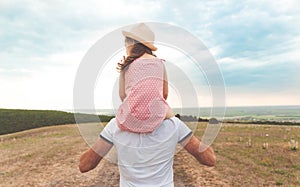 Little girl sitting on father`s shoulders