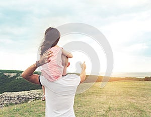 Little girl sitting on father`s shoulders