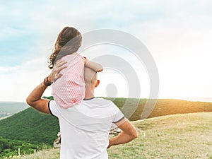 Little girl sitting on father`s shoulders