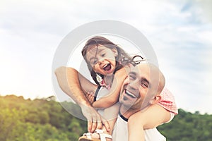 Little girl sitting on father`s shoulders