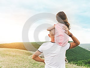 Little girl sitting on father`s shoulders