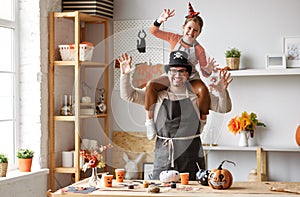 Little girl sitting on father shoulders making scary gesture while making Halloween home decorations