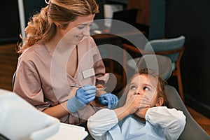 Little girl is sitting with the female doctor. In the stomatological cabinet