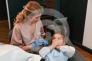 Little girl is sitting with the female doctor. In the stomatological cabinet