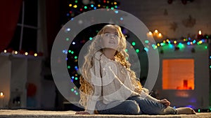 Little girl sitting on floor, waiting Santa on Christmas eve, magical moment