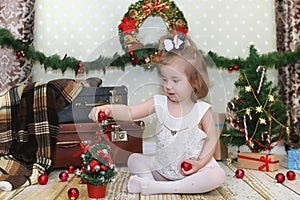 Little girl sitting in front of a Christmas tree