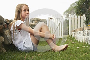 Little Girl Sitting On Grass At Yard