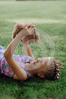 Little girl sitting on the green grass with rabbit. Cute child girl holding a bunny in her hands on Easter day