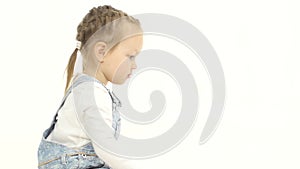 Little girl is sitting on her lap and looking at the laptop. White background