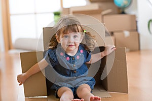 Little girl sitting inside cardboard box in her new home