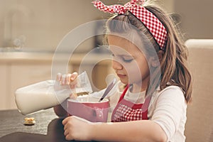 Girl pouring milk into a cereal cup