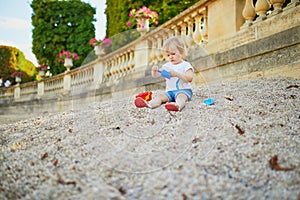 Little girl sitting on a large heap of stones and playing with pebbles