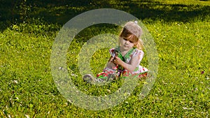 Little girl sitting on the lawn lit by sun