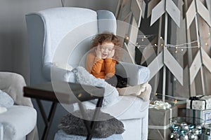 Little girl sitting in the living room near a stylized Christmas tree.