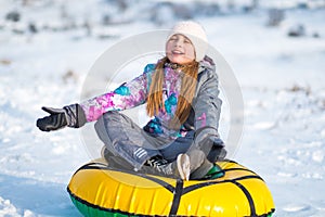 Little girl sitting on tubing snow