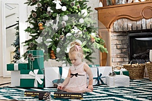 Little girl sitting near Christmas tree