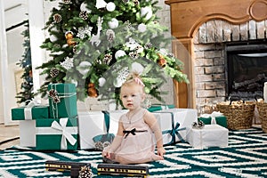 Little girl sitting near Christmas tree