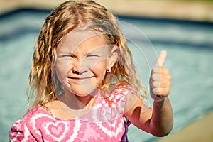 Little girl sitting near swimming pool