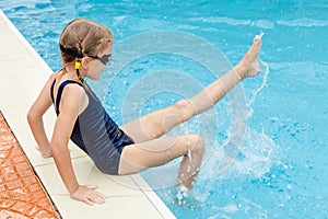 Little girl sitting near swimming pool