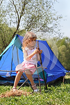 Little girl sitting near tent on nature