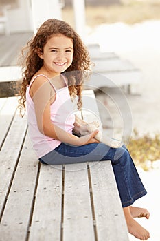 Little girl sitting outdoors holding starfish