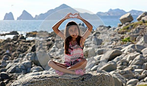 Little girl sitting at rocks at ocean front in Los Cabos Mexico resort cliff sea