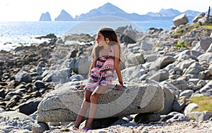 Little girl sitting at rocks at ocean front in Los Cabos Mexico resort cliff sea